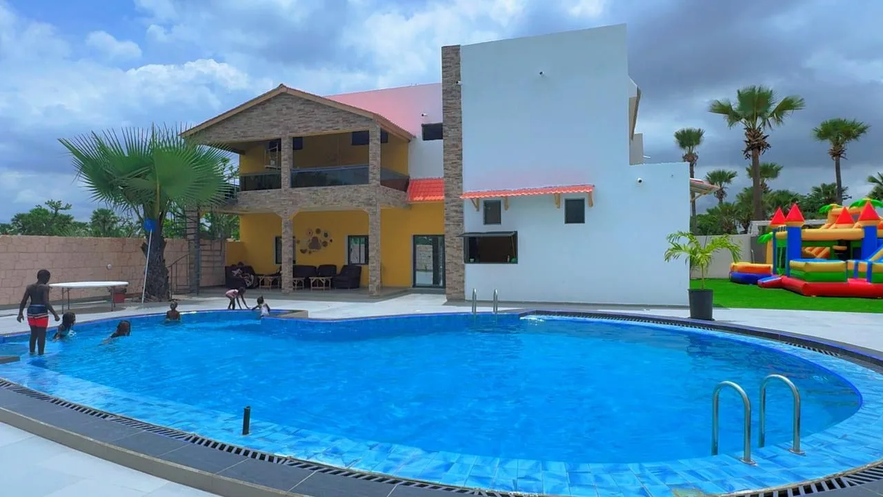 Piscine du parc aquatique Le Petit Village à Thiès, avec le bâtiment et les jeux gonflables